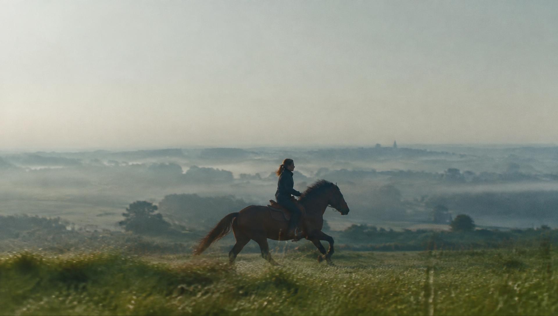 Cavalière au galop dans une prairie brumeuse de Mayenne